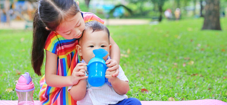 https://newparent.com/wp-content/uploads/2020/07/Adorable-Asian-Sister-Feeding-Baby-with-Sippy-Cup-745x345.jpg